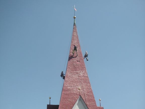 Malerarbeiten an Kirchturm am hängenden Seil